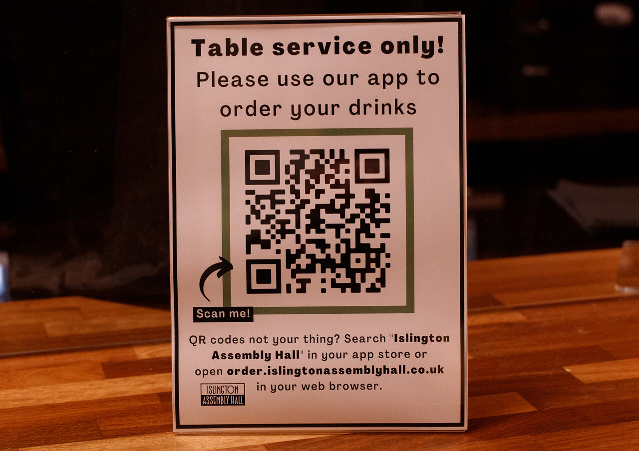 Poster standing on a bar top directing customers to download our app in order to buy drinks for table service